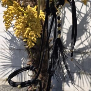 Touwhalster zwart met goud, het Imperial Glow Halster van stevig zwart touw met goudkleurige ringen en een handgemaakt sierhangertje van zwarte en gouden kralen en een zwarte veer – een stijlvol halster voor paarden.