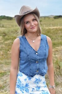 Model in natuurachtergrond, draagt Bluebonnet Ruffle Skirt, Dakota Denim Vest en beige cowboyhoed